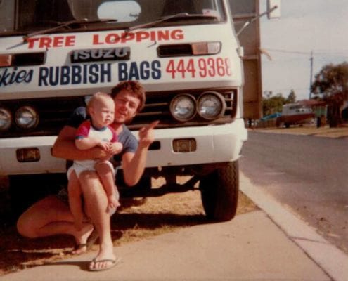 vintage mage of man and toddler in front of old dickies trees truck